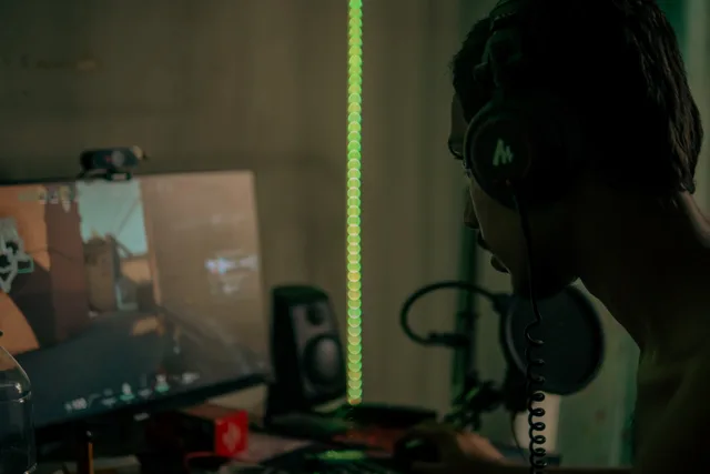 Focused gamer with headset playing a video game on a desktop computer indoors. Five roles in a gaming creator team, mapped to Skills England records